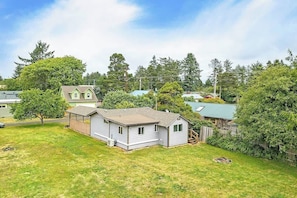 Einbungalow mit eingezäunter Garten, umgeben von Bäumen und anderen Häusern.