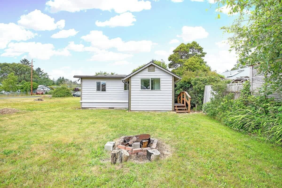 A single-story house with a small backyard, a fire pit, and a wooden deck.