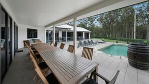 A covered outdoor dining area with a pool and a view of the surrounding trees. - Nu Leaf Retreat (Pokolbin)