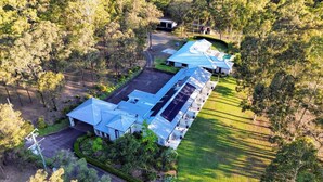 A large building with multiple sections, surrounded by trees and a well-maintained lawn. - Nu Leaf Retreat (Pokolbin)