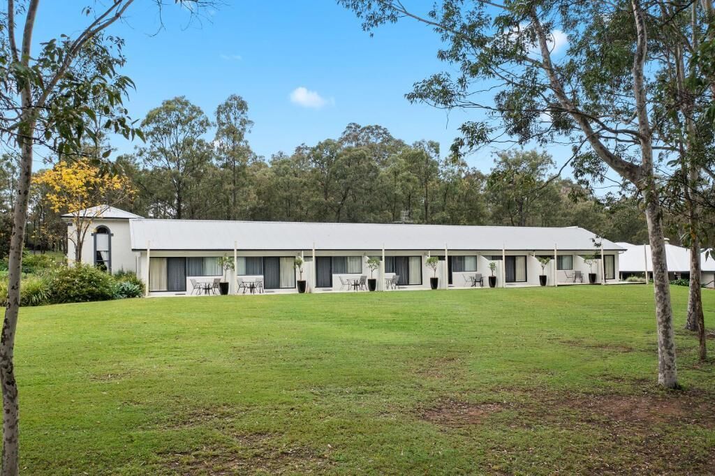 A modern building with a flat roof, multiple rooms with large windows, and a well-maintained lawn.