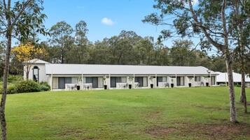 A modern building with a flat roof, multiple rooms with large windows, and a well-maintained lawn.