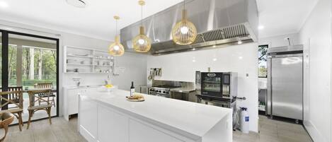 Una cucina moderna con una grande isola, elettrodomestici in acciaio inossidabile e luci a sospensione.