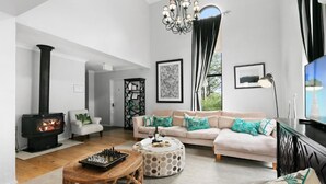 A living room with a fireplace, a sofa, a coffee table, and a chandelier. - Nu Leaf Retreat (Pokolbin)
