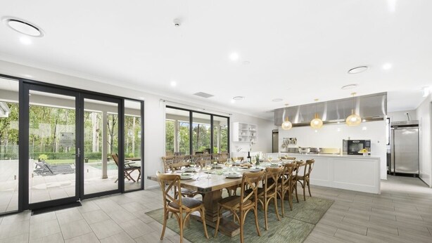 A modern kitchen with a dining area, large windows, and a view of the outdoors. - Nu Leaf Retreat (Pokolbin)