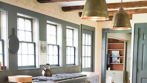 A kitchen with a wooden table, chairs, a stove, and hanging pendant lights. - Quintessential 4-bedroom farmhouse with AC in Kennebunkport (Kennebunkport)