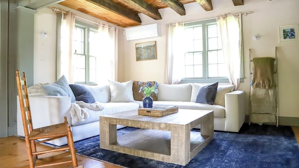 A living room with a white sofa, a wooden rocking chair, a coffee table, and a blue rug. - Quintessential 4-bedroom farmhouse with AC in Kennebunkport (Kennebunkport)