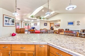 A spacious kitchen with a large island, wooden cabinets, and pendant lighting.