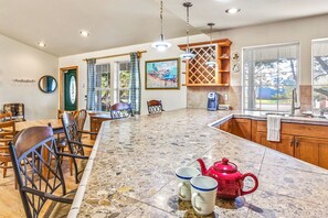 A spacious kitchen with a large island, wooden cabinets, and a dining area with chairs.