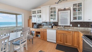 A kitchen with wooden cabinets, a dishwasher, and a view of the ocean. - "Heavenly View" 5 Bedroom, 4 Bathroom, Oceanfront with Private Pool PET FRIENDLY! (Holden Beach)