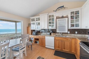 A kitchen with wooden cabinets, a dishwasher, and a view of the ocean. - "Heavenly View" 5 Bedroom, 4 Bathroom, Oceanfront with Private Pool PET FRIENDLY! (Holden Beach)