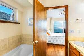 A bathroom with a bathtub, a wooden door, a window, and a mirror.