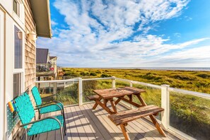 A wooden deck with a table and chairs, overlooking a grassy landscape.