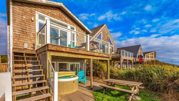 A wooden house with a deck, a hot tub, and a picnic table. - Beachfront w/ Hot Tub | Sleeps 11 | Dogs OK (Ocean Shores)