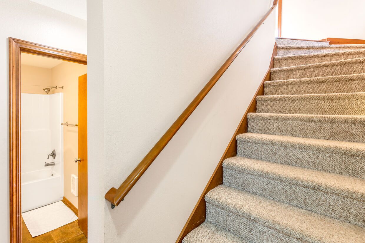 A staircase with carpeted steps and a wooden handrail.