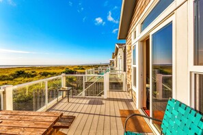 A wooden deck with a glass balustrade overlooking a beach.