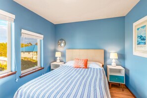 A bedroom with a bed, two bedside tables, a window, and a wall clock.