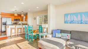 A modern kitchen with wooden cabinets, a refrigerator, and a dining area with chairs and a table. - Beachfront w/ Hot Tub | Sleeps 11 | Dogs OK (Ocean Shores)