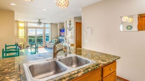 A kitchen with a granite countertop, double sink, wooden cabinets, and pendant lighting. - Beachfront w/ Hot Tub | Sleeps 11 | Dogs OK (Ocean Shores)