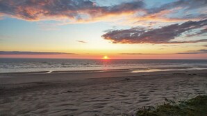A beach with a sunset, clear sky, and calm sea. - Beachfront w/ Hot Tub | Sleeps 11 | Dogs OK (Ocean Shores)