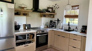 A modern kitchen with a built-in oven, a stove, a sink, and a window with blinds.