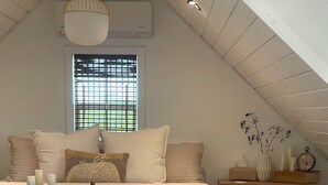 A bedroom with a bed, bedside table, lamp, and window.