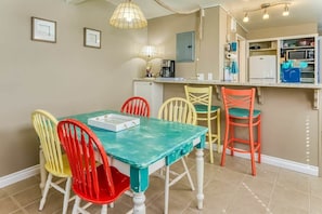 A dining area with a table and chairs, a kitchen area with appliances, and a counter. - Beachfront Condo | Walk to DT | Dogs OK | Unit A (Ocean Shores)