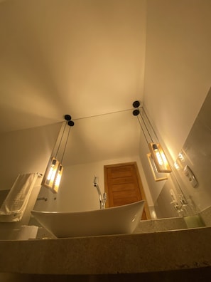 A bathroom with a freestanding bathtub, a wooden door, and pendant lights. - Casa Ilhéus Pousada (Ilheus)