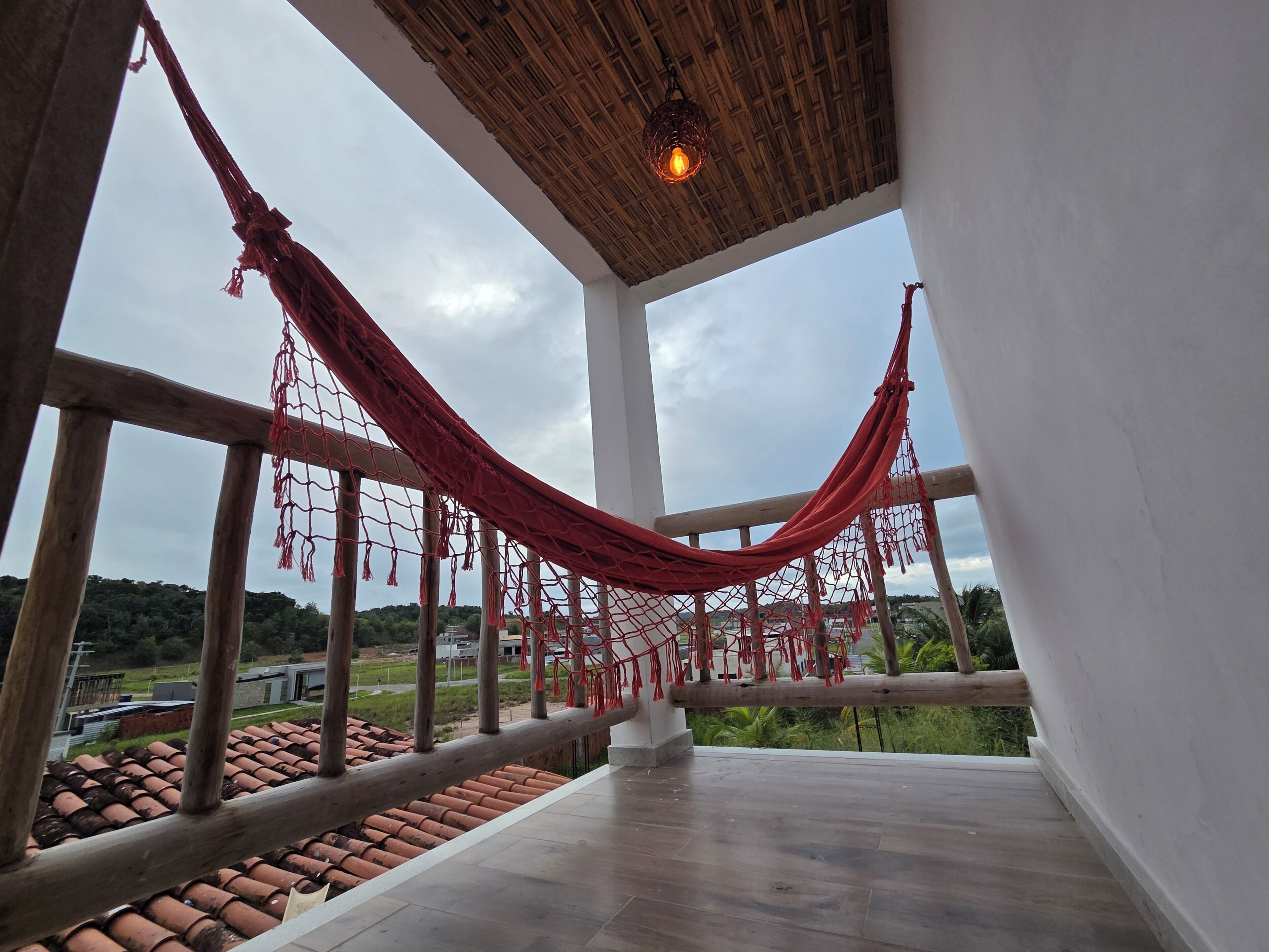A room with a hammock, large windows, and a view of the landscape.