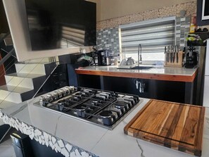 Una cocina moderna con estufa a gas, encimera de madera y salpicadero con mosaicos.