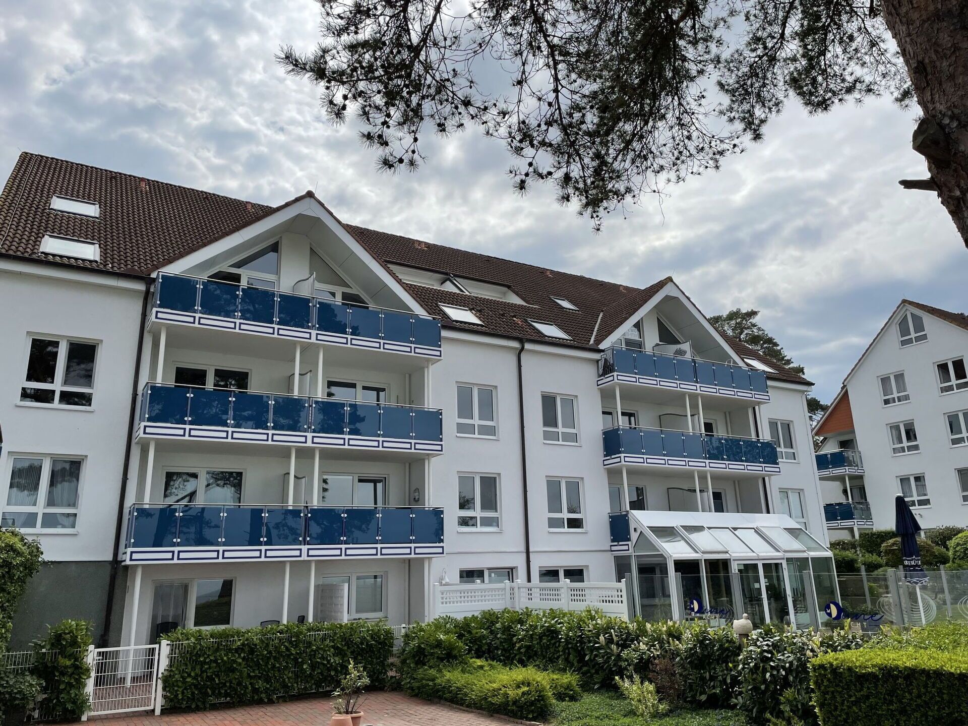 A multi-story residential building with balconies, a gated entrance, and a glass conservatory.