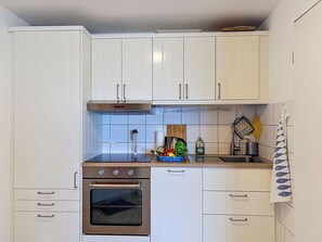 Eine Küche mit weißen Schränken, einem Edelstahlbackofen und einer Holz Arbeitsplatte.