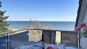 Ein Balkon mit einem Tisch für zwei Personen, mit Blick auf ein Gewässer.