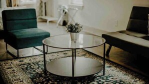 A modern living room with a round glass coffee table, a green armchair, and a sofa. - The Blue Heron-elegant urban studio in city center (Memphis)