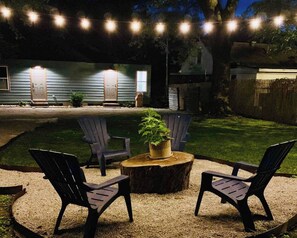 Un jardin avec une table en bois, deux chaises et un pot de fleurs.