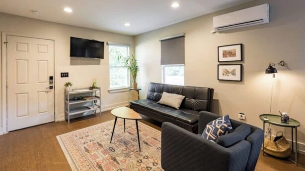 Een woonkamer met een bank, een salontafel, een aan de muur bevestigde televisie en een airconditioning.