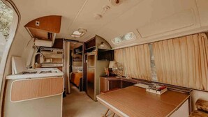 Interior compacto de una autocaravana con kitchenette, zona de comedor y pequeño espacio habitable.