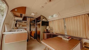 Interior compacto de una autocaravana con kitchenette, zona de comedor y pequeño espacio habitable.