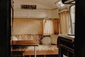 Een gezellig interieur van een camper met een bank, een tafel en een fornuis.