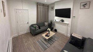 Una sala de estar moderna con un sofá, una mesa de centro, un televisor y una chimenea.