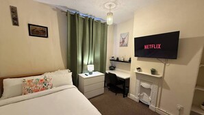 Habitación de hotel con cama, escritorio, silla, televisor y chimenea.