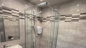 Un baño moderno con ducha acristalada, lavabo blanco y retrete.