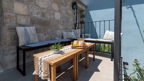 Ein Balkon mit einer Steinmauer, Holzmöbeln und einem Metallgeländer.