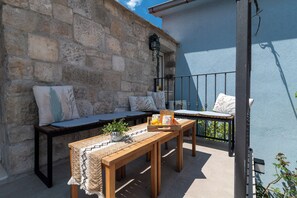 A balcony with a stone wall, wooden furniture, and a metal railing. - Traditional stone house w terrace, near the beach (Trogir)