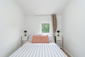 A bedroom with a bed, two bedside tables, a window, and a view of greenery outside. - Traditional stone house w terrace, near the beach (Trogir)