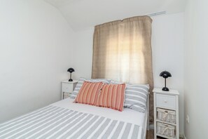 A bed with striped bedding, a beige curtain, and two bedside tables with lamps. - Traditional stone house w terrace, near the beach (Trogir)