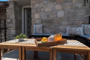 A wooden table with a tray of food and drinks, a potted plant, and a stone wall in the background. - Traditional stone house w terrace, near the beach (Trogir)