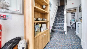 Um corredor com um armário de madeira, uma escada com carpete estampado e uma porta que dá para outro quarto.