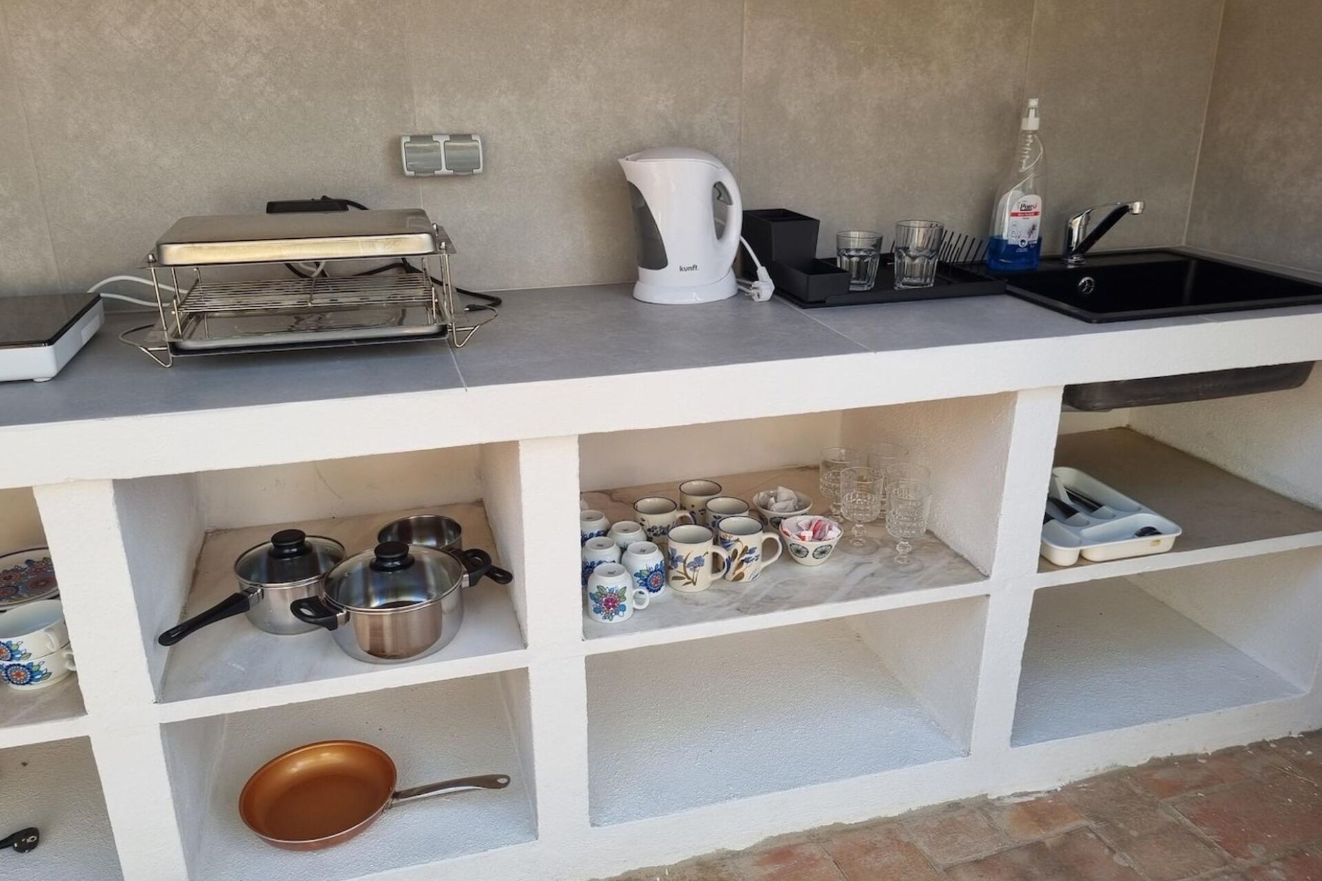A kitchenette with a coffee maker, kettle, and various kitchenware.