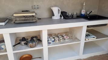 A kitchenette with a coffee maker, kettle, and various kitchenware.